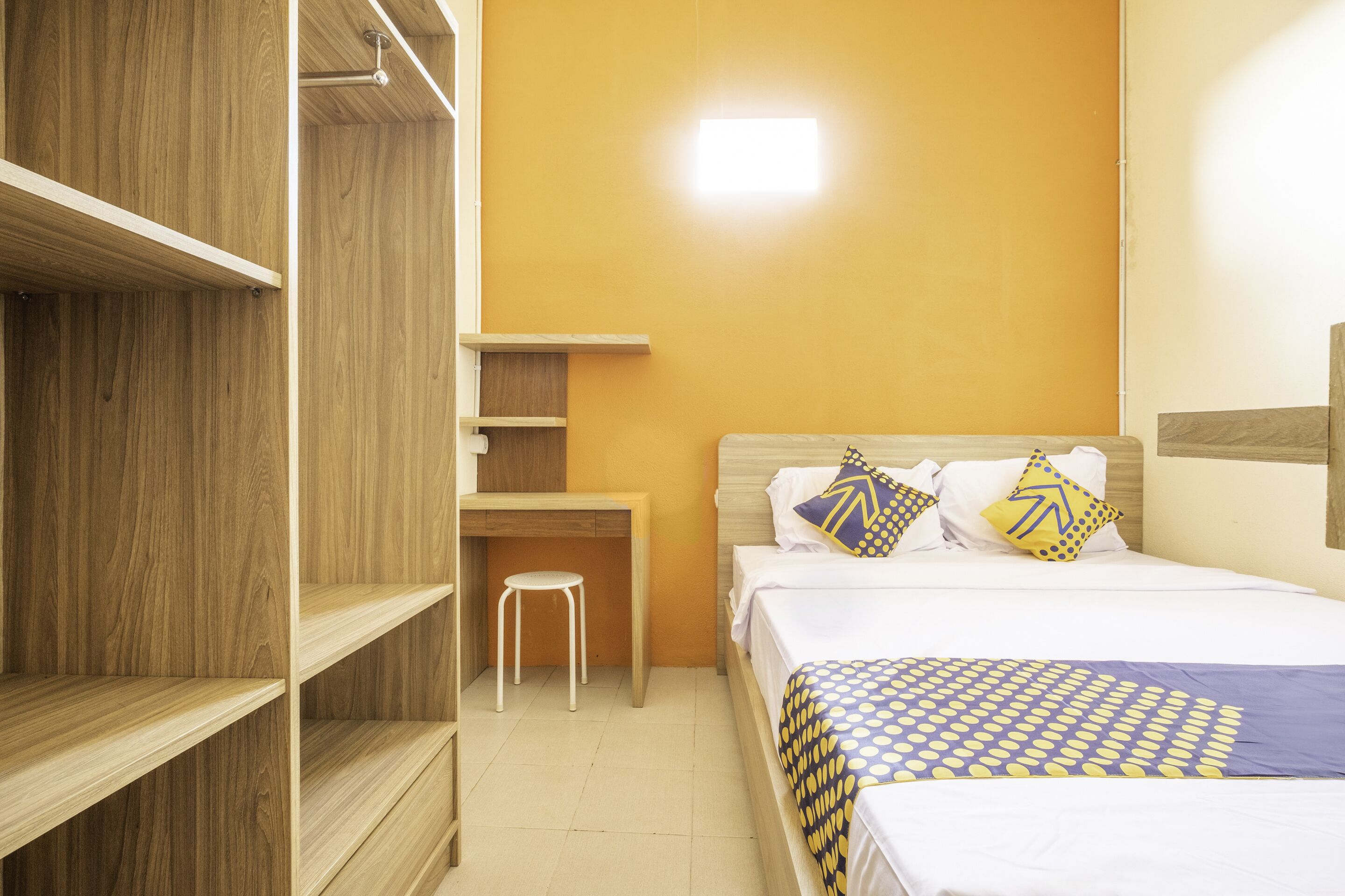 A bedroom with a bed, a desk, and a wardrobe.