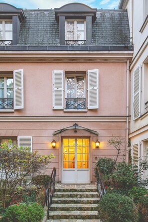 A two-story building with a pink facade, white shutters, and a stone staircase leading to the entrance. - Hôtel des Grandes Ecoles (Paris)