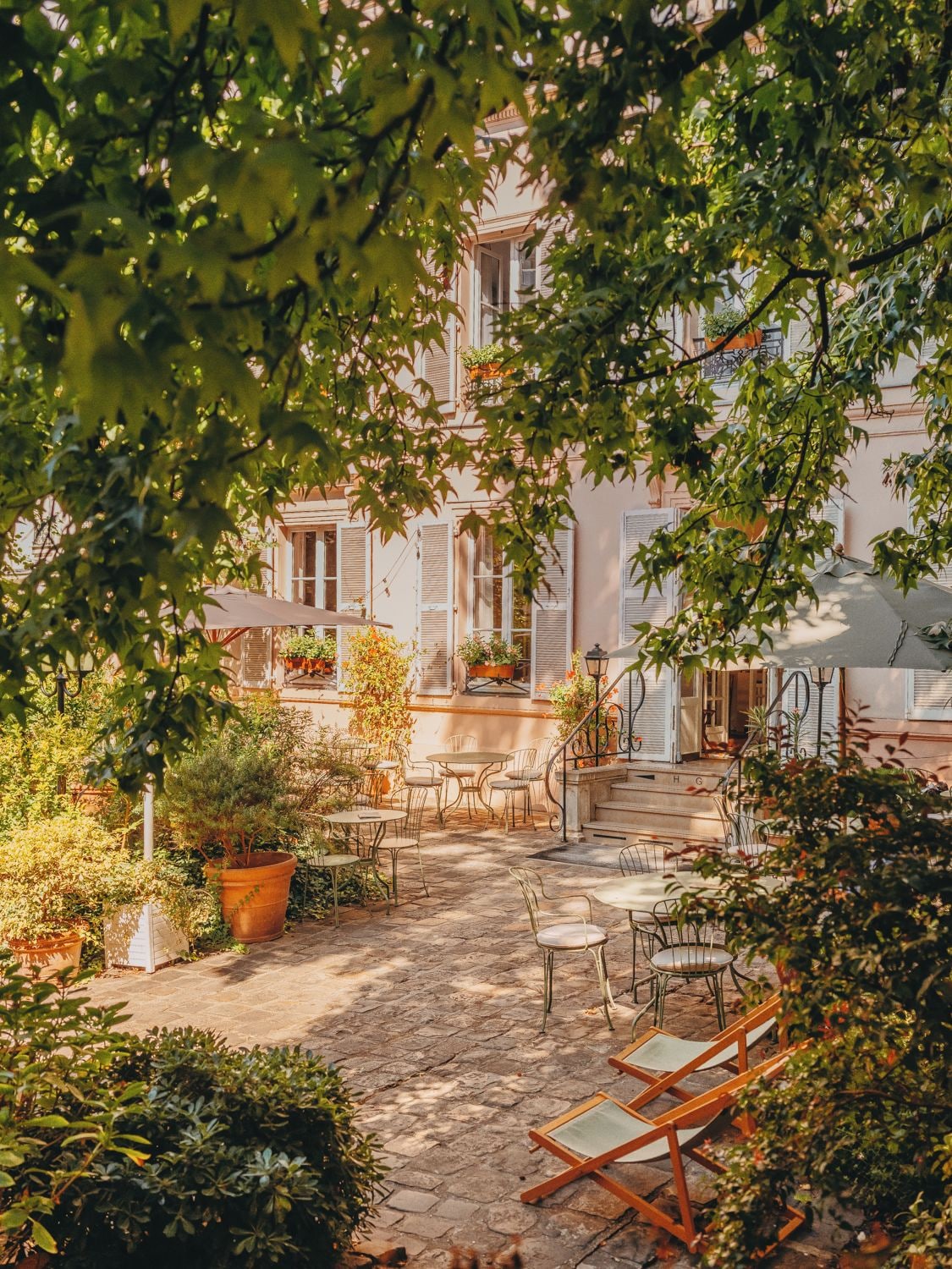 An outdoor courtyard with stone flooring, outdoor seating, and potted plants.