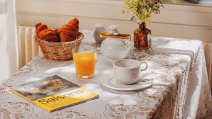 A breakfast table with croissants, a glass of orange juice, a cup, saucer, and a book titled 'Saison'. - Hôtel des Grandes Ecoles Quartier Latin (Paris)