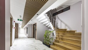 A modern hotel lobby with a marble floor, a staircase with wooden steps, and a plant near the stairs. - Dem İstanbul Airport Hotel (Istanbul)