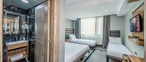 Una habitación de hotel con baño, dos camas, televisión y un espejo grande.