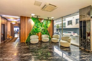 Un hall d’entrée avec un mur végétal, un sol en marbre et quatre chaises.