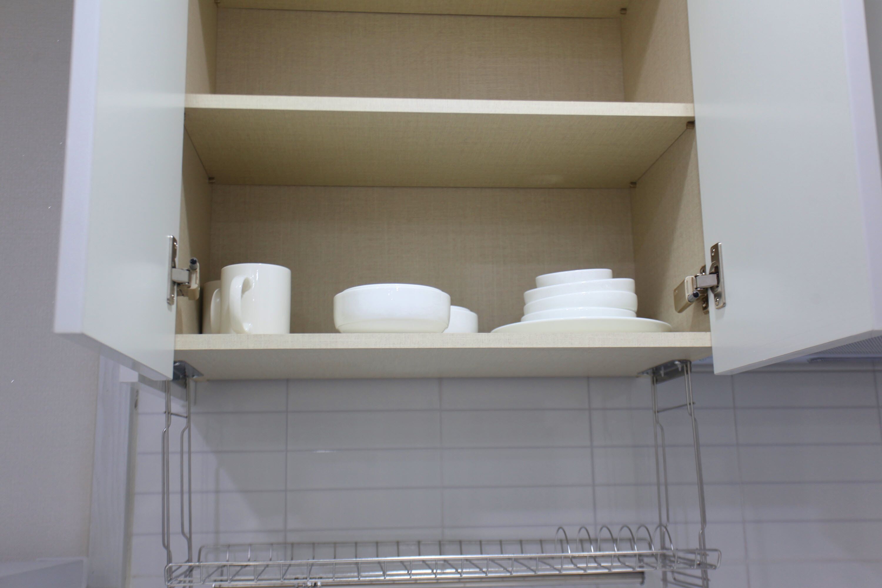 Un meuble de cuisine contenant de la vaisselle blanche et une étagère en métal.