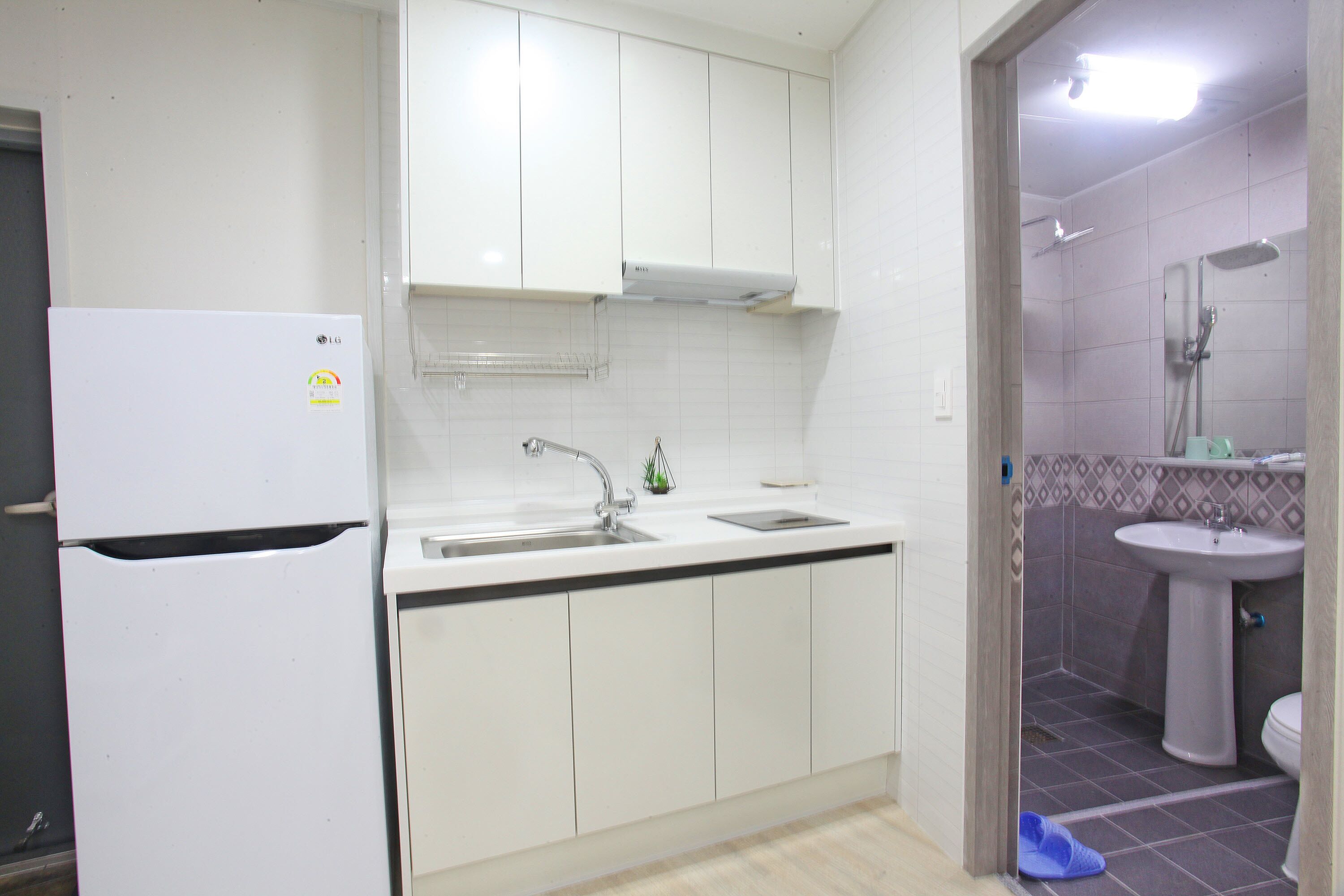 A kitchen with white cabinets, a sink, and a refrigerator.
