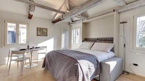 A bedroom with a bed, a bedside table, a chair, and a window. - Venice Skyline View Sudio Apartment (Venice)