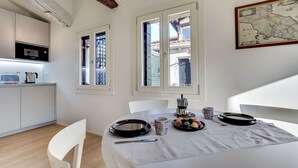 A dining area with a white table, chairs, and a map on the wall. - Venice Skyline View Sudio Apartment (Venice)