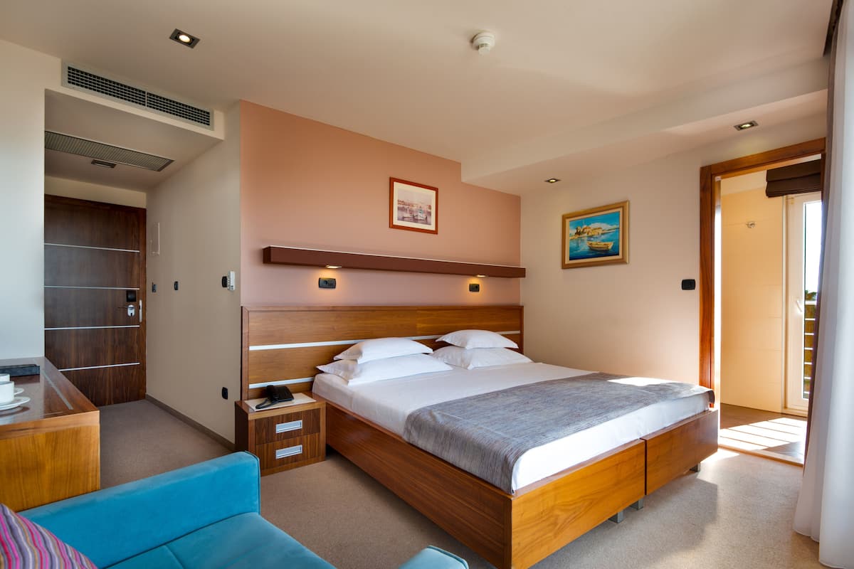 Ein modernes Schlafzimmer mit einem Holzbett, einem Schreibtisch und einem blauen Sofa.