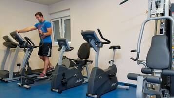 Un gimnasio con cintas de correr, elípticas y equipo de pesas.