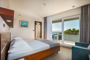 Une chambre d’hôtel avec un lit, une chaise, un tableau et un balcon offrant une vue.