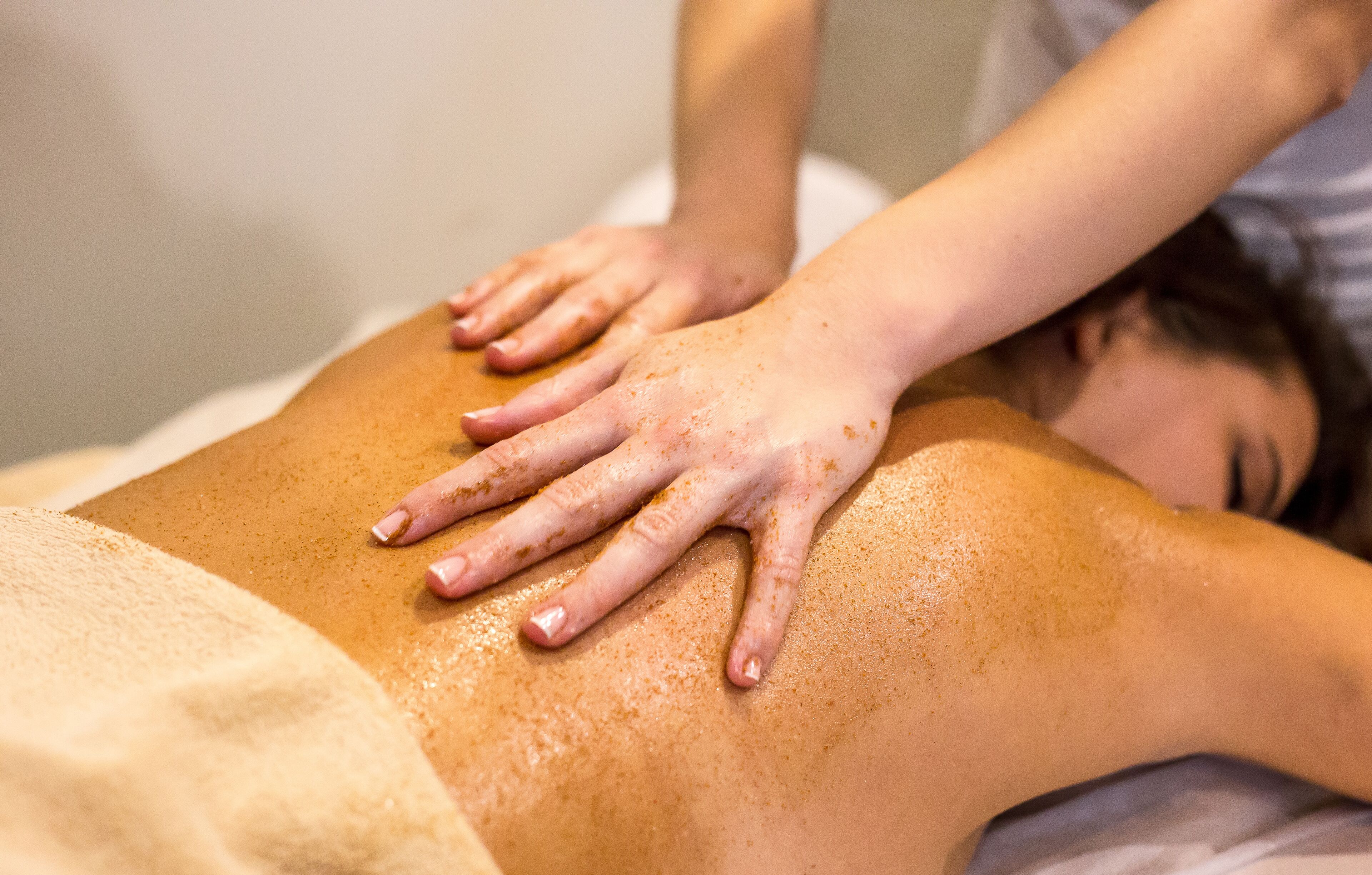 A person receiving a massage with hands on their back.