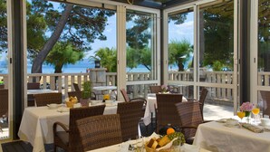 A restaurant with outdoor seating overlooking a beach, featuring wicker chairs and white tablecloths. - Hotel Plaza Omis (Omis)
