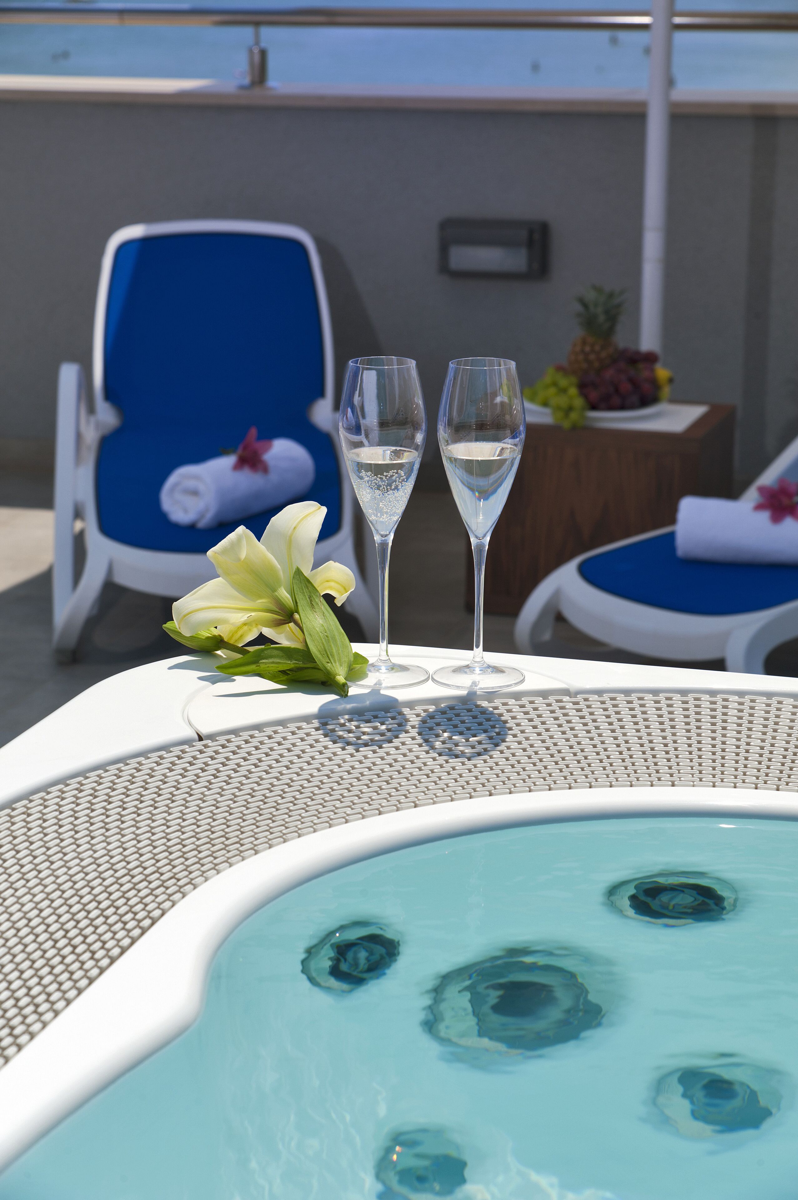 Una vasca idromassaggio con due flute di champagne e un fiore su un tavolo.