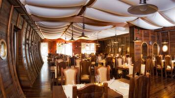Een restaurant met houten wanden en plafond, ronde tafels en stoelen.