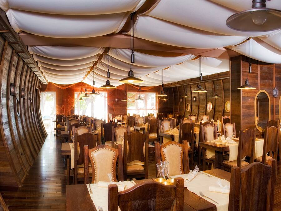 Un restaurante con paredes y techo de madera, mesas redondas y sillas.
