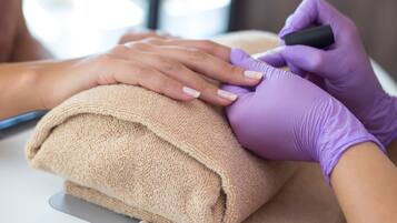 A close-up of hands receiving a manicure.