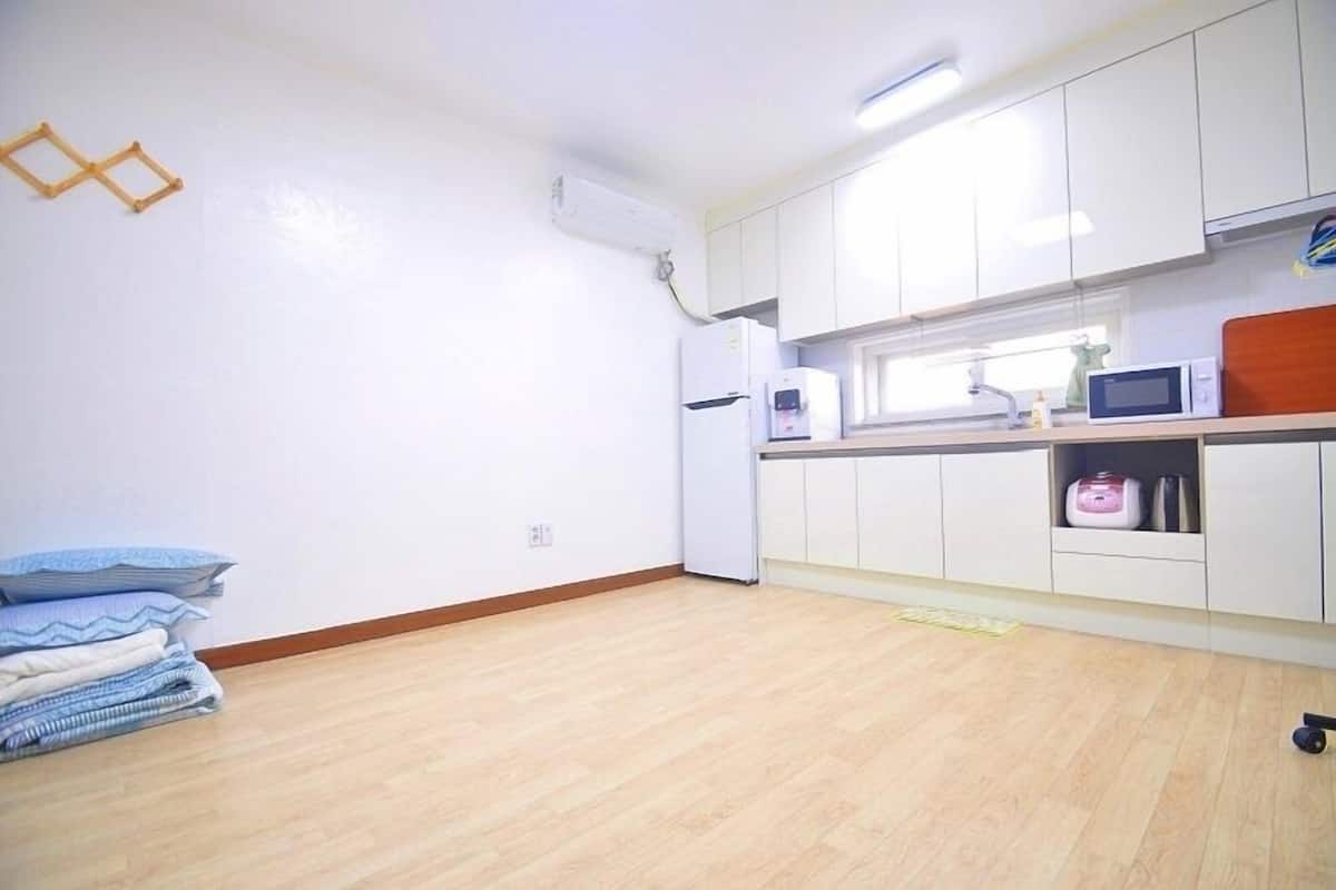 A small, bright kitchen with white cabinets, a microwave, and a refrigerator.