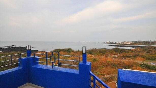 A coastal view with a blue railing and a clear sky. - Osio Pension (Jeju City)