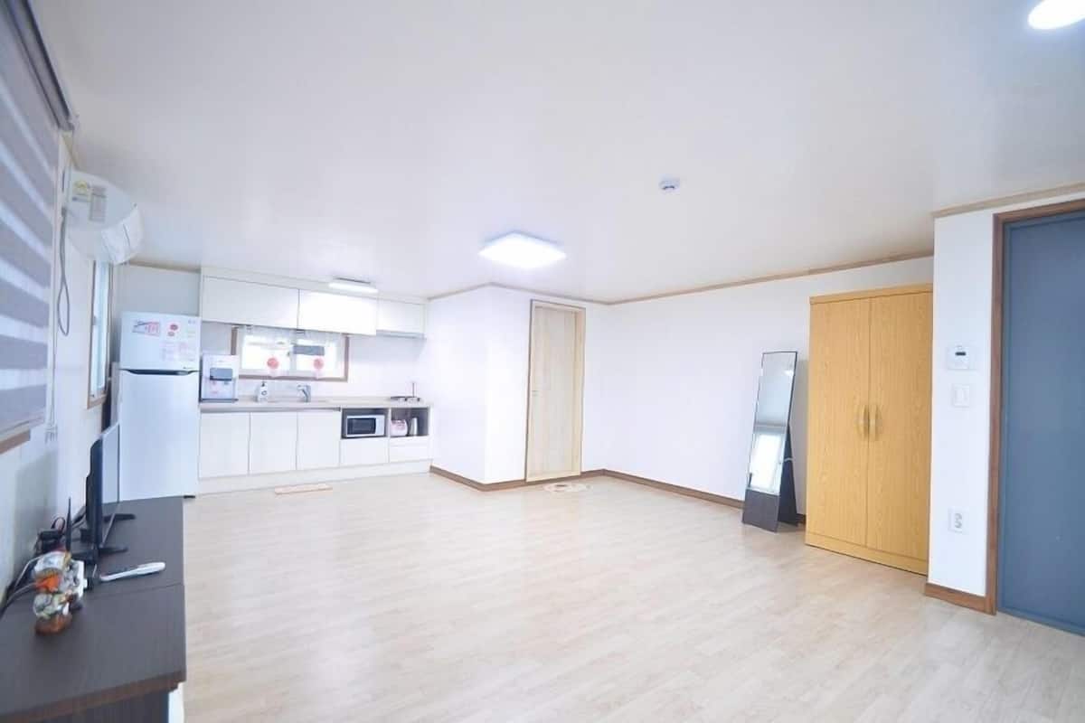 A spacious living area with a kitchen, wooden flooring, and a large wardrobe.