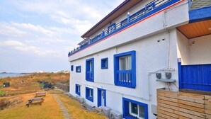 A two-story building with blue-framed windows and a balcony. - Osio Pension (Jeju City)