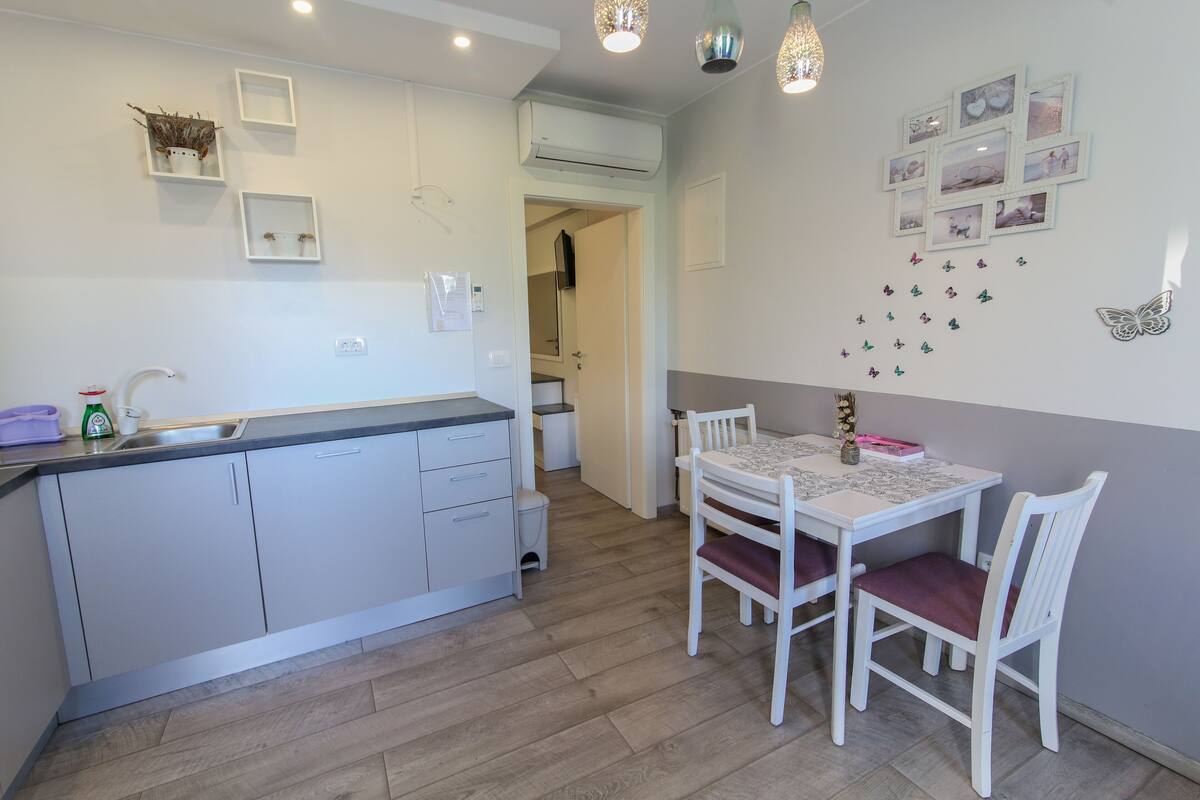 Una cocina compacta con armarios blancos, un lavabo y una zona de comedor con mesa y sillas.