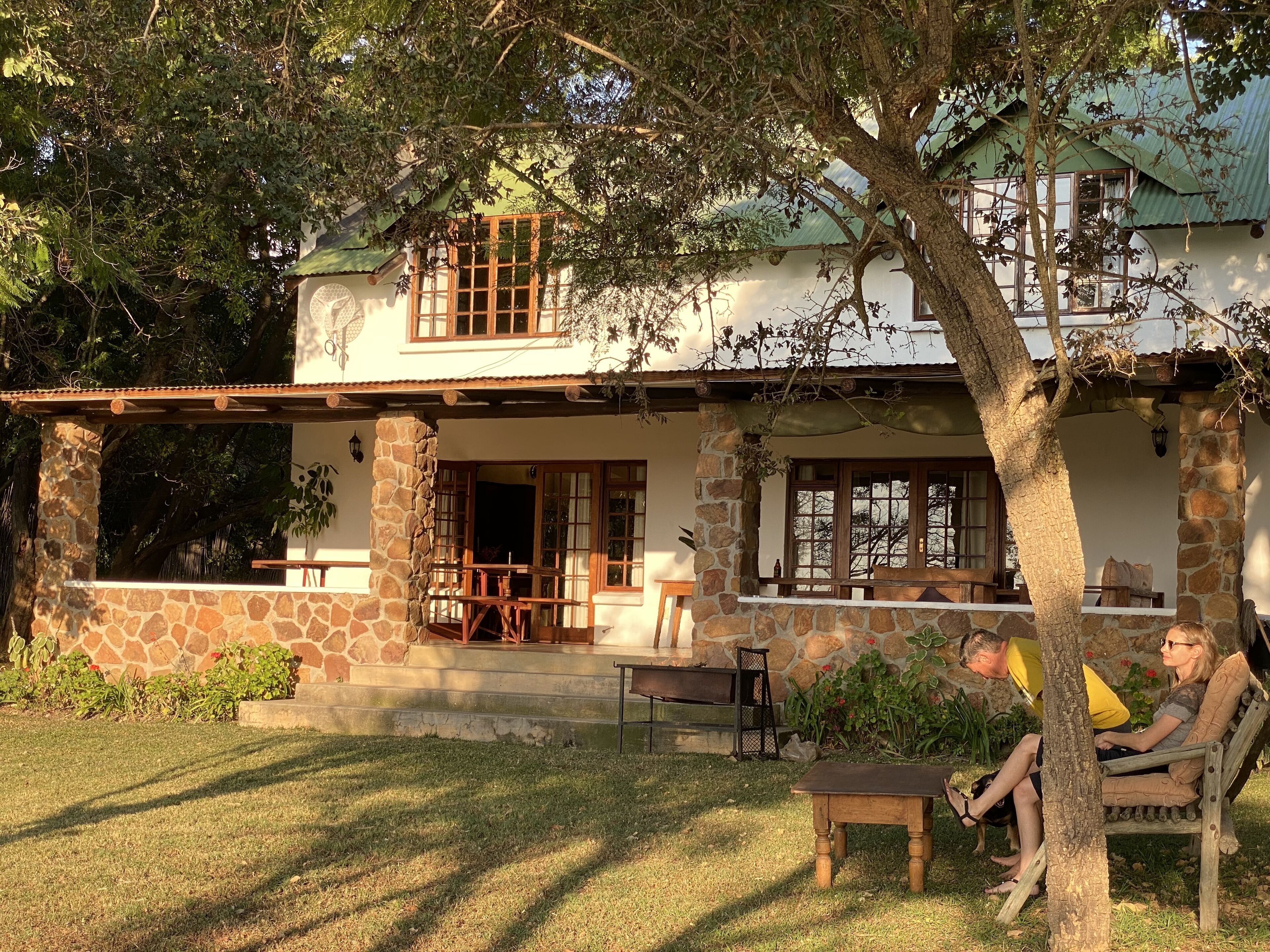 A two-story house with stone pillars, a covered porch, and a dining area.