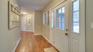 A hallway with wooden flooring, white walls, and a door with windows. - Waterfront Deck + Dock: Torch Lake Home! (Rapid City)