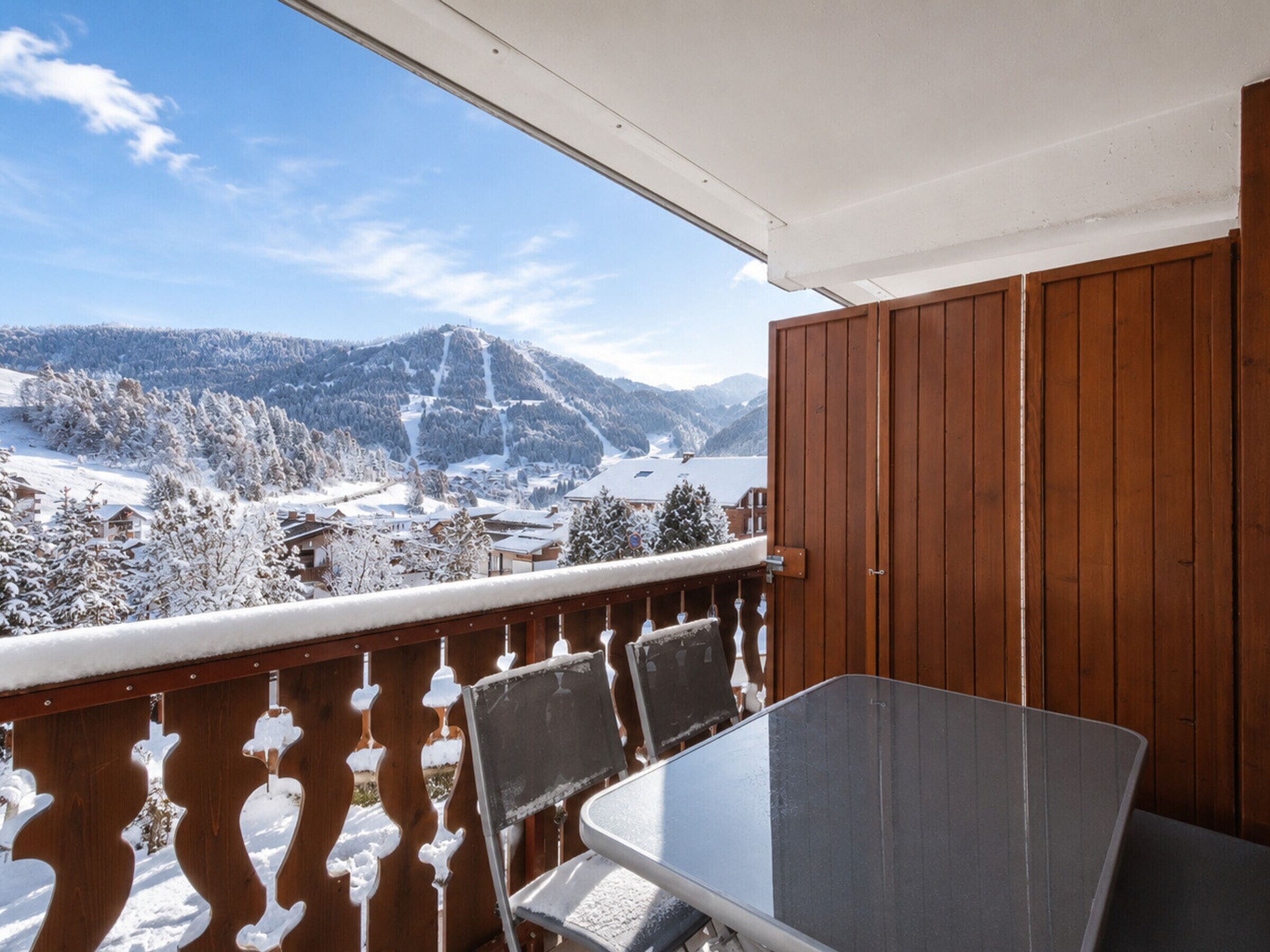 Un balcon avec une table et des chaises, donnant sur un paysage montagneux enneigé.