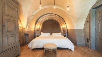 A bedroom with a large bed, an arched ceiling, and wooden flooring.