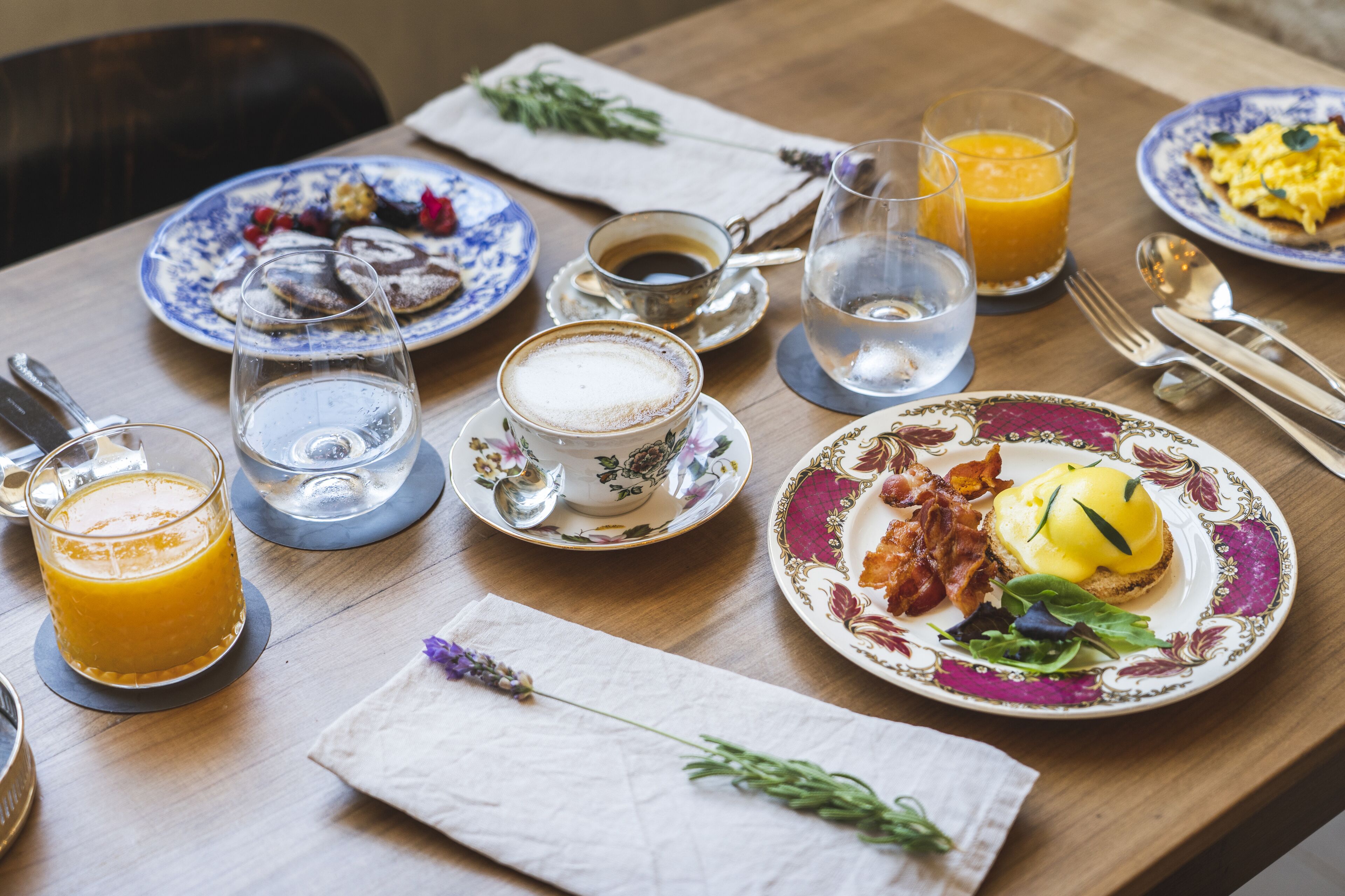 Una colazione con piatti di cibo, bicchieri di succo d'arancia e una tazza di caffè.
