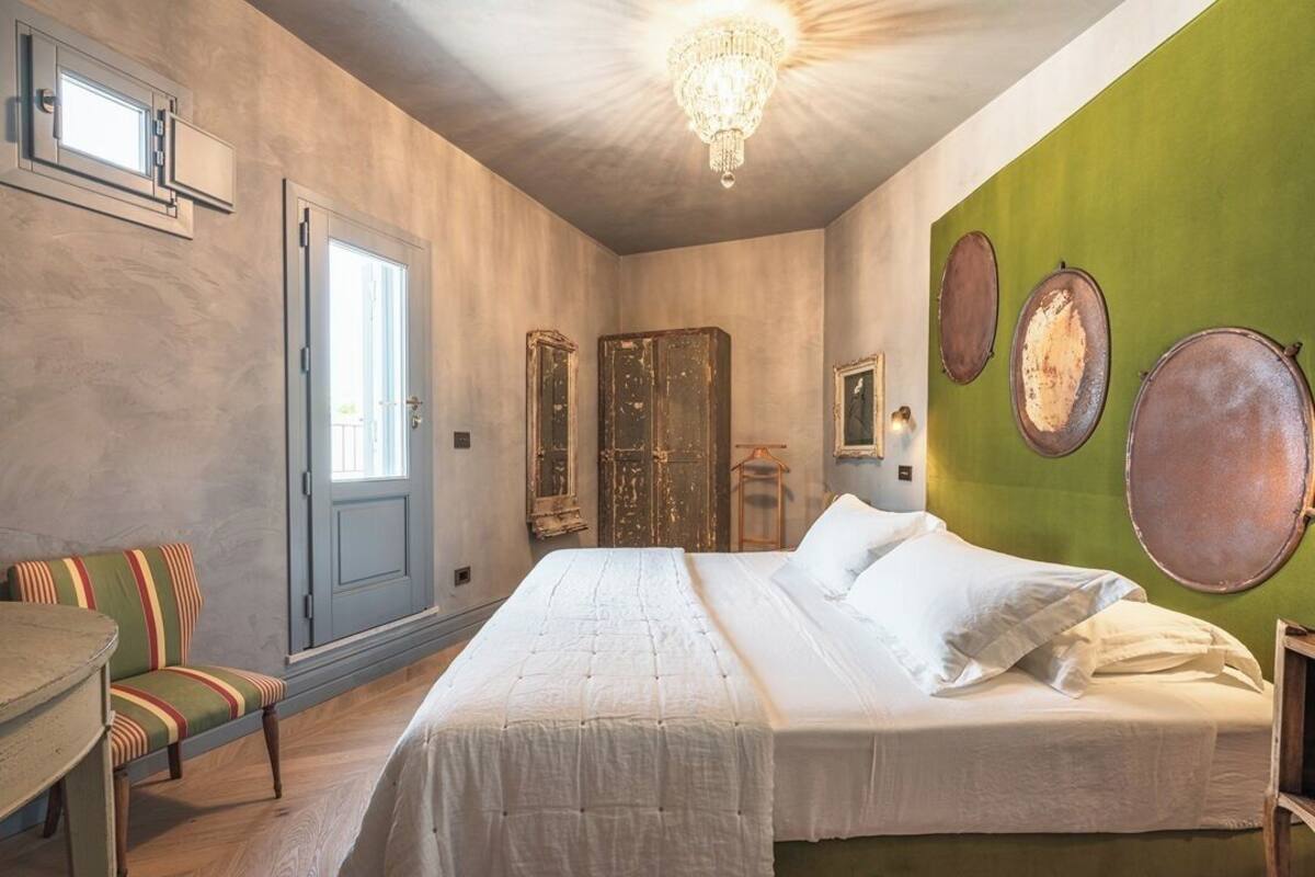 A bedroom with a bed, a chair, a table, and a chandelier.