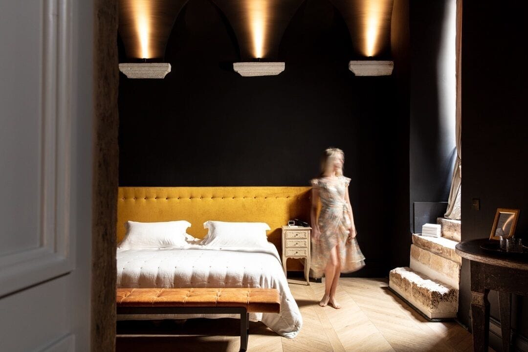 Une chambre à coucher avec un grand lit, un banc en bois, une table de chevet et un escalier.