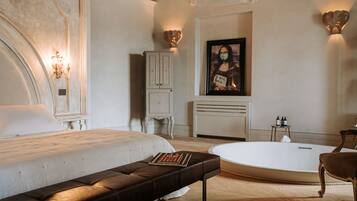 Een moderne slaapkamer met een groot bed, een bankje, een badkuip en een kast.