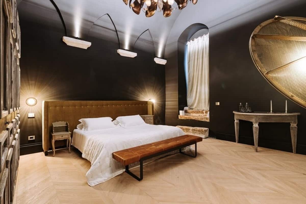 A modern bedroom with a large bed, wooden bench, and a unique ceiling light fixture.