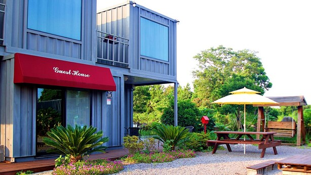 A modern building with a red awning labeled "Guest House." - Wedding House (Seogwipo)