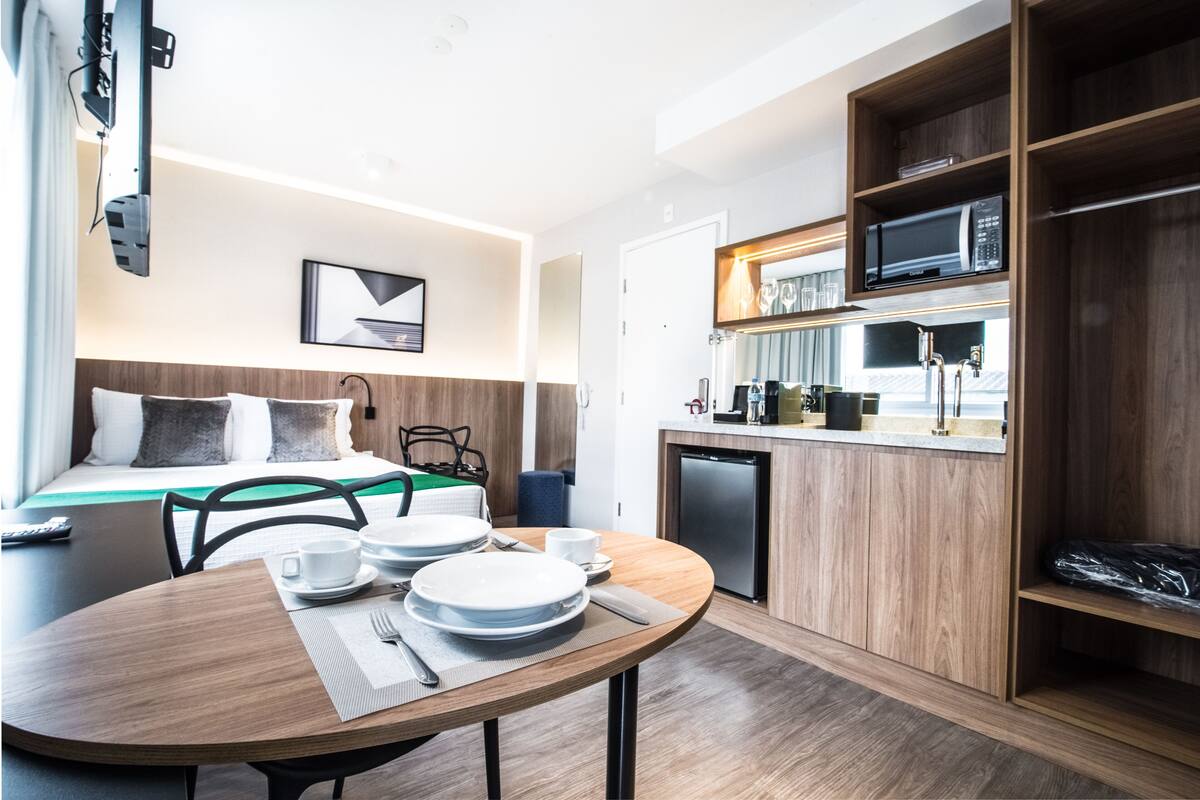 Habitación de hotel compacta con comedor, kitchenette y cama con vistas.