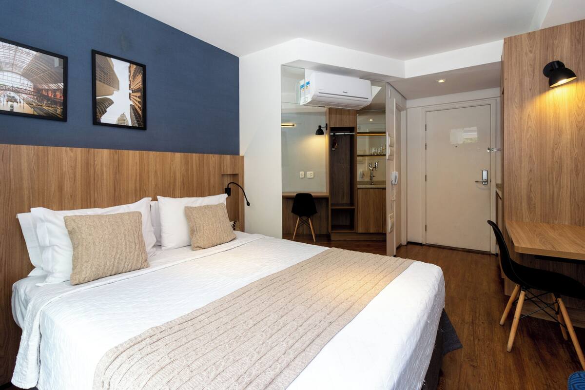 Una habitación de hotel con una cama grande, cabecera de madera, un escritorio y un armario.
