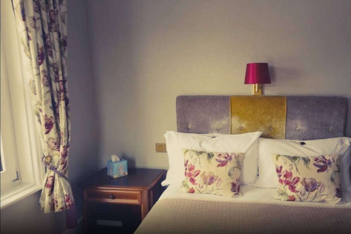 Ein Hotelzimmer mit Bett, Nachttisch, Lampe und Tür.