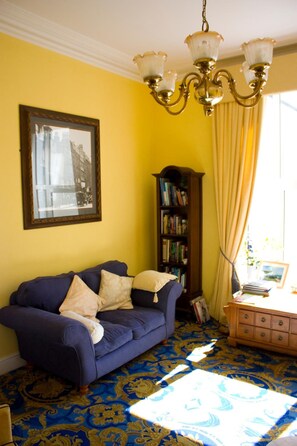 A room with a blue sofa, a wooden bookshelf, and a patterned carpet. - 17 Wilmington Square (Eastbourne)