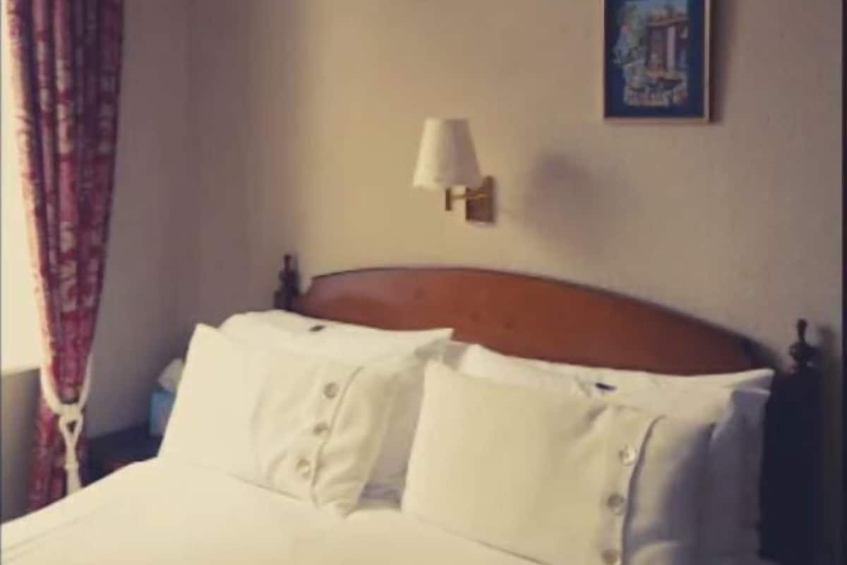Ein Hotelzimmer mit einem Bett, einer Wandlampe und einem gerahmten Bild.