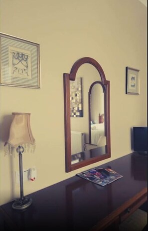 A hotel room with a dark wooden desk, a framed mirror, a lamp, and a magazine. - 17 Wilmington Square (Eastbourne)
