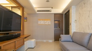 A modern living room with a flat-screen TV, wooden entertainment unit, white ottoman, grey sofa, and a small white table. - Comfy & Central 2B1b, Sleeps 5, 3min to Daan MRT (Taipei)