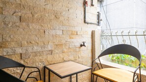 A stone wall with a small table and two chairs, a window with a view of greenery, and a water spigot. - Comfy & Central 2B1b, Sleeps 5, 3min to Daan MRT (Taipei)