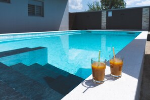 Una piscina amb dos gots de tes glaçat al vorell.