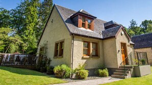 Una casa a due piani con tetto spiovente, un portico e un piccolo giardino.