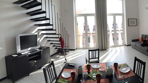 A modern living room with a dining area, featuring a staircase, a flat-screen TV, and a sofa with cushions. - SweetHomeToledo Historical Center (Napoli)