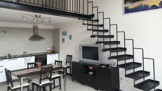 A modern kitchen with a dining area, a staircase, and a mounted painting. - SweetHomeToledo Historical Center (Napoli)