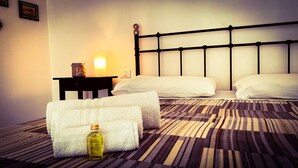 A hotel room with a bed, two pillows, a bedside table with a lamp, a bottle of lotion, and a framed picture on the wall. - SweetHomeToledo Historical Center (Napoli)