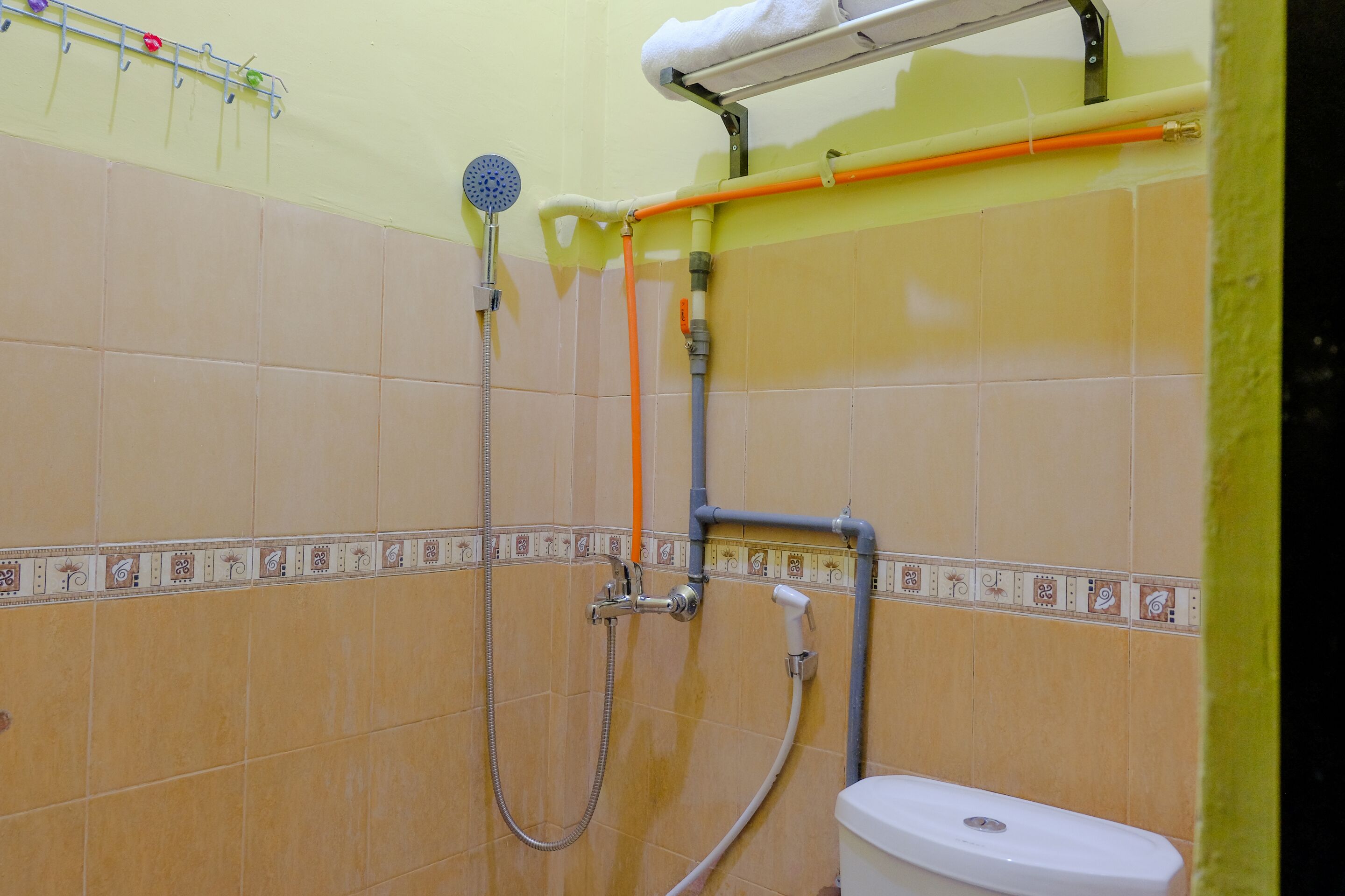 A bathroom with beige tiles, a shower, a toilet, and a towel rack.