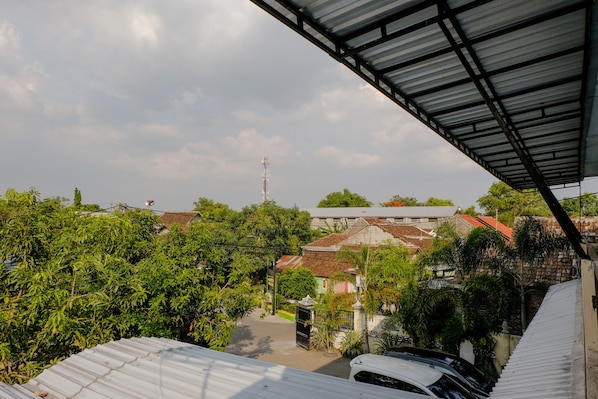 A residential area with a metal roofed structure, greenery, and buildings with red-tiled roofs.